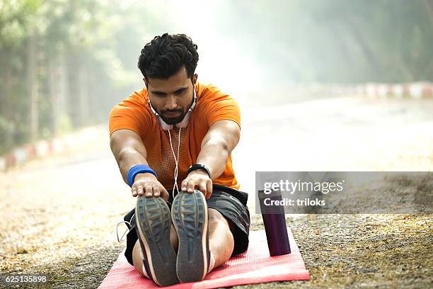 man stretching on yoga mat at park - tocar nos dedos dos pés imagens e fotografias de stock