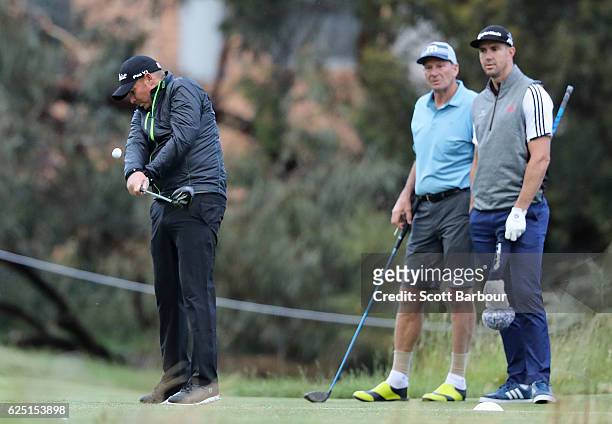 Shane Warne tees off as former cricketer Kevin Pietersen and former AFL player Sam Newman look on on Pro-Am Day ahead of the World Cup of Golf at...