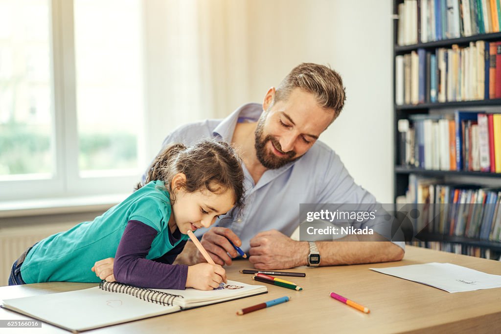 Father and daughter drawing together at home