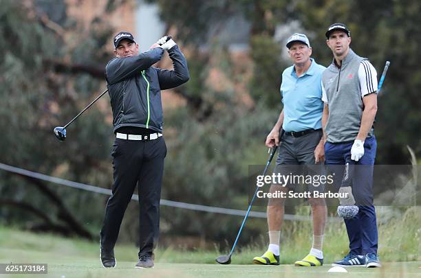 Shane Warne tees off as former cricketer Kevin Pietersen and former AFL player Sam Newman look on on Pro-Am Day ahead of the World Cup of Golf at...