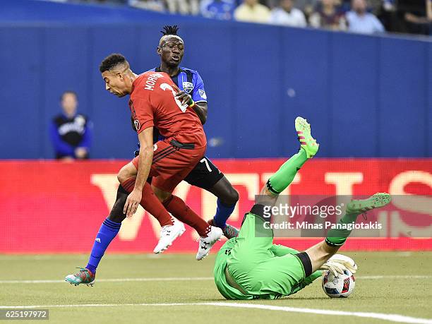 Goaltender Clint Irwin makes a save while Justin Morrow of the Toronto FC defends against Dominic Oduro of the Montreal Impact during leg one of the...