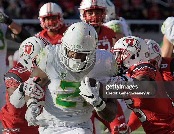 Running back Royce Freeman of the Oregon Ducks tries to run through tacklers defensive back Marcus Williams and defensive back Dominique Hatfield of...