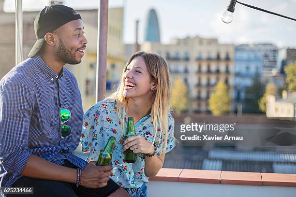 cheerful couple holding beer bottles on terrace - beer cap stock pictures, royalty-free photos & images