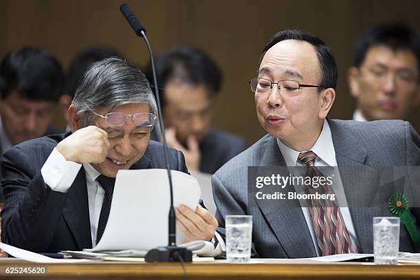 Haruhiko Kuroda, governor of the Bank of Japan , left, reacts as Masayoshi Amamiya, an executive director at the BOJ, looks over his shoulder during...