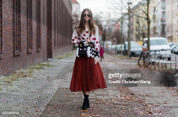 Jennifer Amanda wearing a colorful mohair sweater from Twin Set, a pleated midi skirt from Baum und Pferdgarten in burtn henna, black slim-fitting...