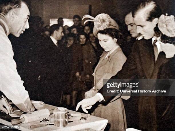 Photograph of Queen Elizabeth II and Prince Philip, Duke of Edinburgh at the Pastry Making Exhibit at Olympia. Dated 20th Century.