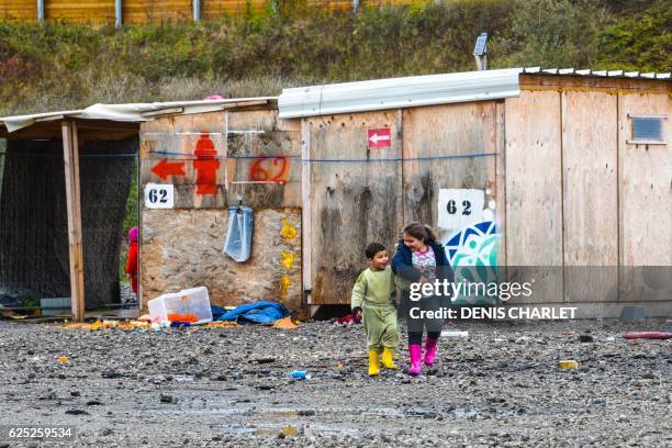 Children walk at a camp for migrants and refugees in Grande-Synthe, northern France, on November 18, 2016. - Ever since the evacuation of the...