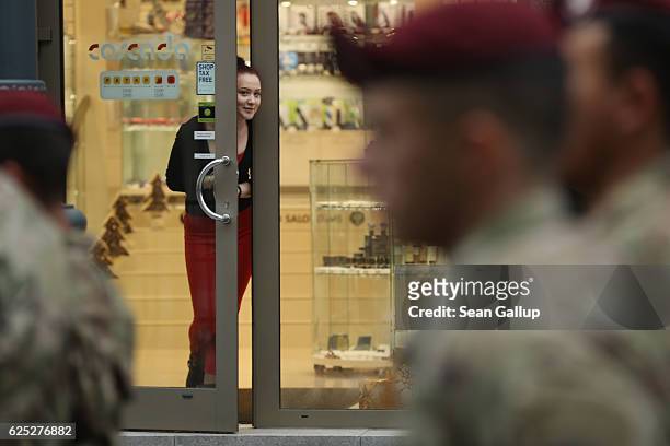 Young woman peeks from a shop door as soldiers of the U.S. 173rd Airborne Brigade march past in a parade during the Iron Sword multinational military...