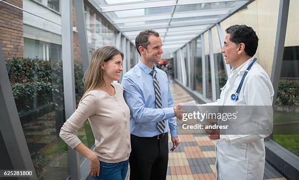 arzt begrüßt patienten im krankenhaus - couple shaking hands with doctor stock-fotos und bilder