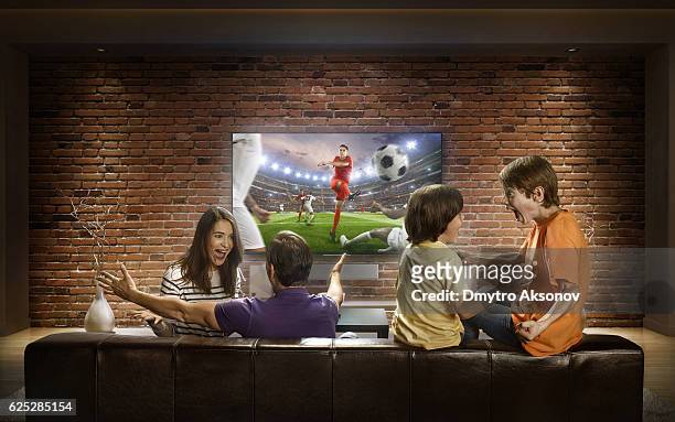 la famiglia sta guardando la partita di calcio a casa - calciare foto e immagini stock