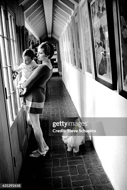 American actress and musician Barbra Streisand holds her son, Jason, in a hallway in their home, Beverly Hills, California, 1967.