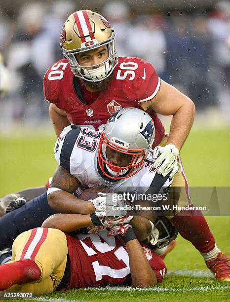 Dion Lewis of the New England Patriots carries gets tackled by Keith Raser and Nick Bellore of the San Francisco 49ers in the third quarter of their...