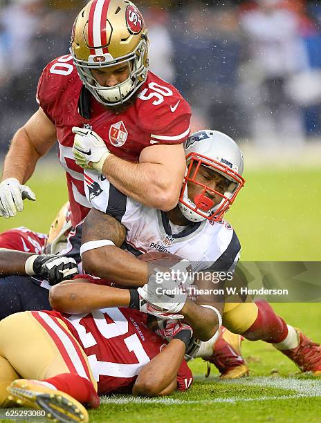 Dion Lewis of the New England Patriots carries gets tackled by Keith Raser and Nick Bellore of the San Francisco 49ers in the third quarter of their...