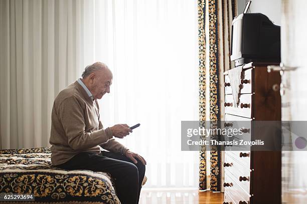 senior man watching television - trabalho fastidioso - fotografias e filmes do acervo
