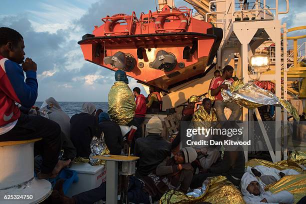 Refugees sit wrapped in survival blankets to keep warm on board the Topaz Responder, MOAS' 'Migrant Offshore Aid Station's' search and rescue vessel...