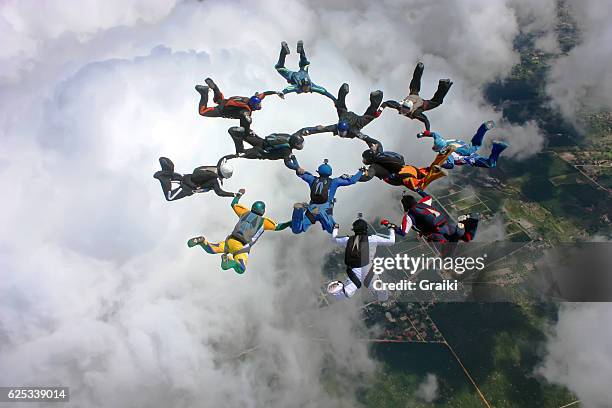 skydivers make a formation above the clouds - parachute stock pictures, royalty-free photos & images