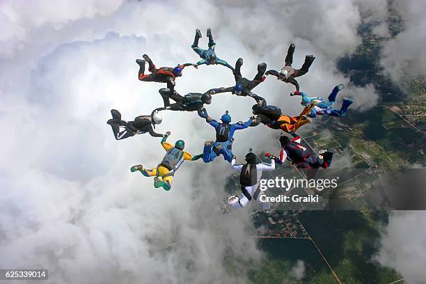 skydivers make a formation above the clouds - happy ending stock pictures, royalty-free photos & images