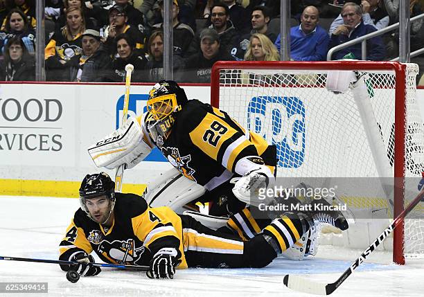 Justin Schultz of the Pittsburgh Penguins reaches for the puck while laying on the ice against the New York Rangers at PPG PAINTS Arena on November...