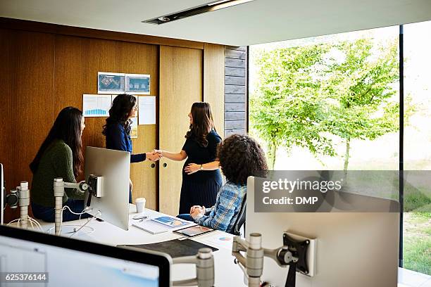 two businesswoman shaking hands in office - pregnant women greeting stockfoto's en -beelden