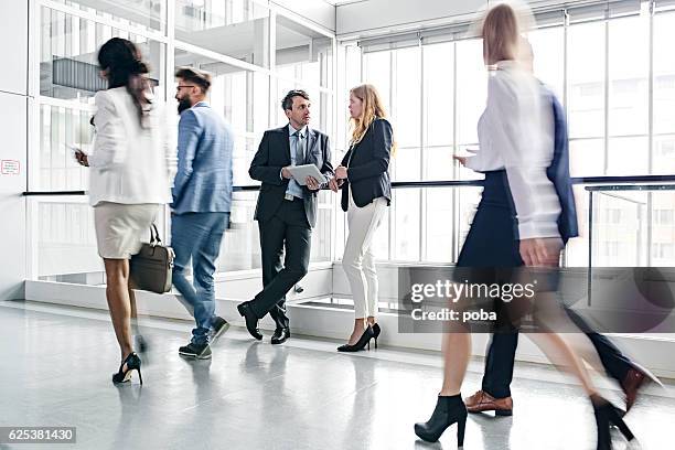businesspeople walking in busy office building - trång kostym bildbanksfoton och bilder