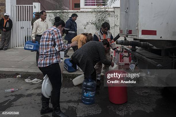 Neighbours collect water in buckets and bins from a water truck in a residential area affected by the lack of water in the city of La Paz, Bolivia on...