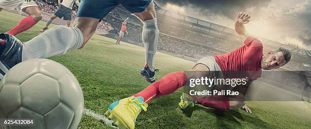 jugador de fútbol en deslizamiento abordar durante el partido de fútbol en el estadio - delantero fotografías e imágenes de stock