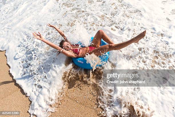 young woman in a blue rubber ring enjoying the beach - brown hair waves stock pictures, royalty-free photos & images