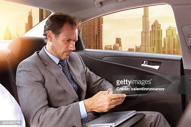 middle eastern businessman traveling in car - limousine stock pictures, royalty-free photos & images