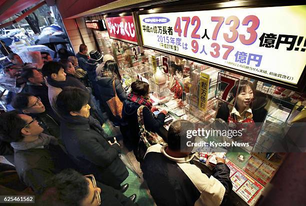 People line up in front of a booth in Tokyo's Ginza commercial district to buy the year-end "Jumbo" lottery tickets, which went on sale on Nov. 24,...