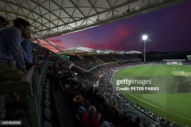 Visitors watch as the sun sets during the first innings of the day-night third Test cricket match between Australia and South Africa at the Adelaide...