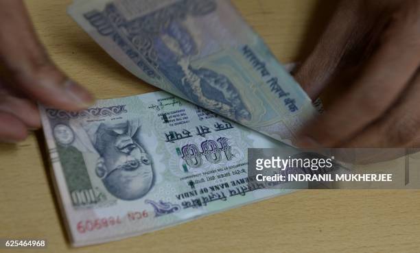 Bank staff member counts Indian 100 rupee notes to give to customers on November 24 in the wake of the demonetisation of old 500 and 1000 rupee notes...