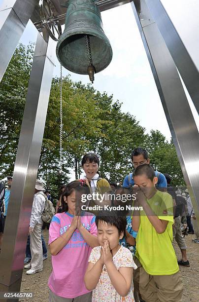 Japan - Children pray after tolling a bell for the souls of the victims of the 1985 Japan Airlines jumbo jet at the crash site called Osutaka Ridge...