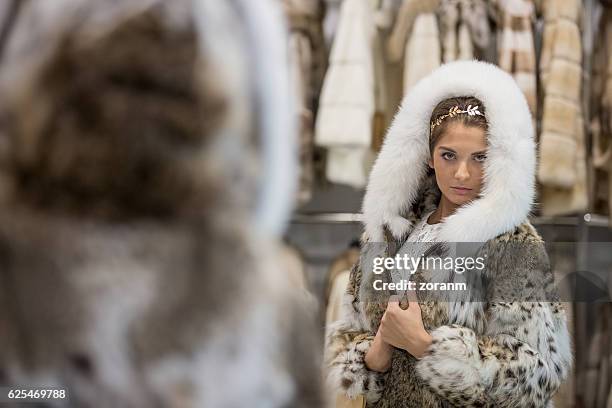 femme essayant un manteau de fourrure en magasin - pardessus photos et images de collection