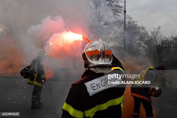 Firefighters brandish smoke flares as they demonstrate on Place de la Nation in Paris on November 24, 2016 as part of a nationwide strike to denounce...