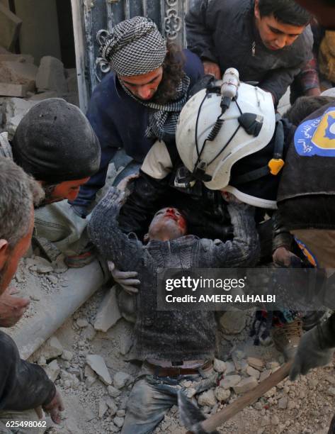 Syrian civil defence volunteers, known as the White Helmets, rescue a boy from the rubble following a reported barrel bomb attack on the Bab...