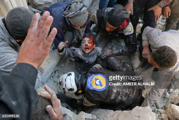 Syrian civil defence volunteers, known as the White Helmets, rescue a boy from the rubble following a reported barrel bomb attack on the Bab...