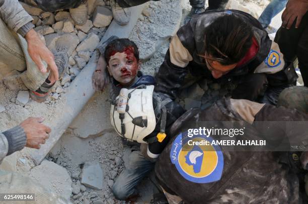 Syrian civil defence volunteers, known as the White Helmets, rescue a boy from the rubble following a reported barrel bomb attack on the Bab...