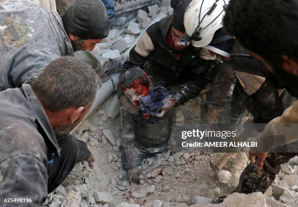 Syrian civil defence volunteers, known as the White Helmets, rescue a boy from the rubble following a reported barrel bomb attack on the Bab...