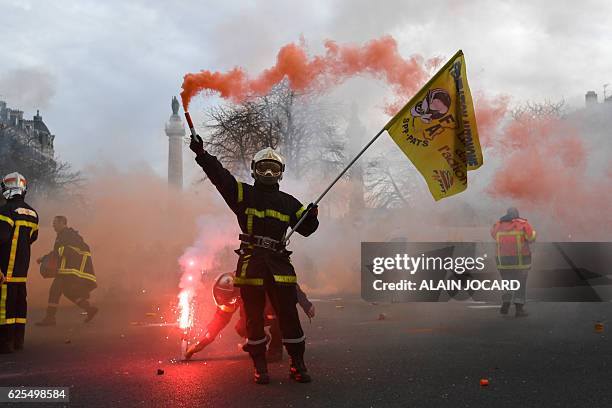 Firefighters brandish smoke flares as they demonstrate on Place de la Nation in Paris on November 24, 2016 as part of a nationwide strike to denounce...