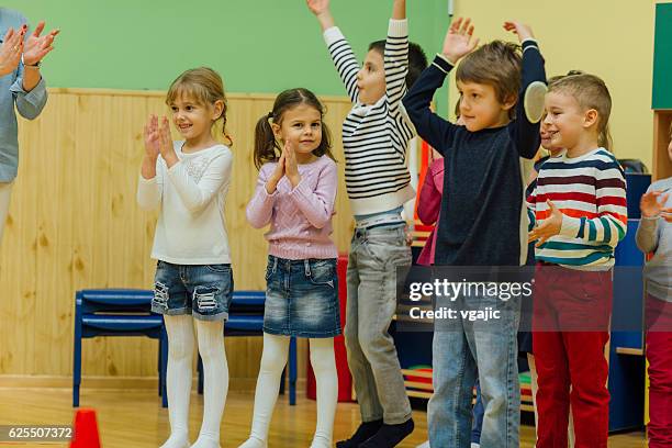 group of children playing with their teacher in kindergarten - class hula hoop stockfoto's en -beelden