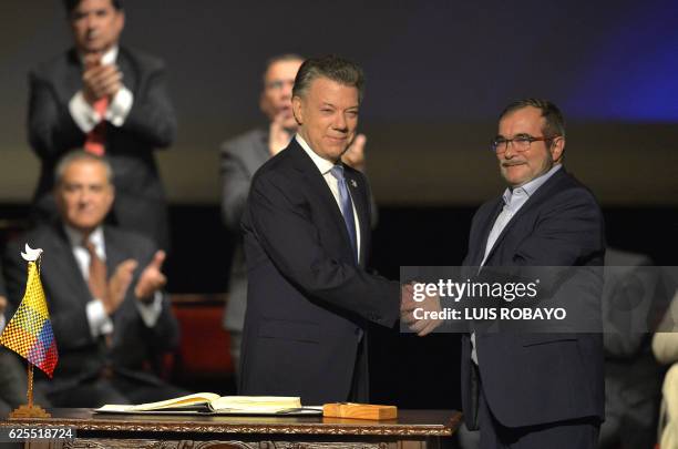 Colombian President Juan Manuel Santos and the head of the FARC guerrilla Timoleon Jimenez, aka Timochenko, shake hands during the second signing of...