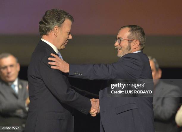 Colombian President Juan Manuel Santos and the head of the FARC guerrilla Timoleon Jimenez, aka Timochenko, shake hands during the second signing of...