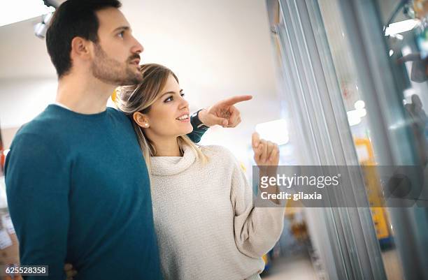 buying food in supermarket. - couple pointing imagens e fotografias de stock