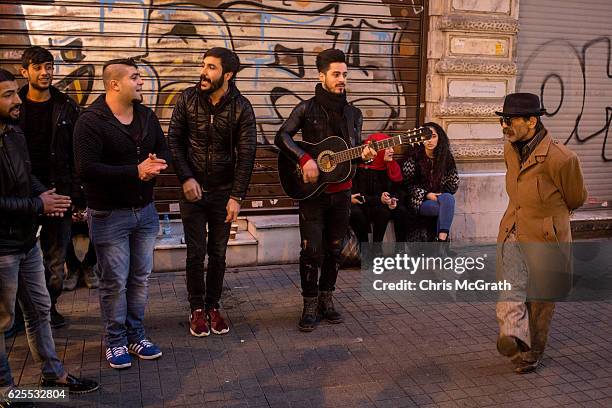 Man dances to music played by buskers outside a closed shop on Istanbul's famous Istiklal shopping street on November 24, 2016 in Istanbul, Turkey....