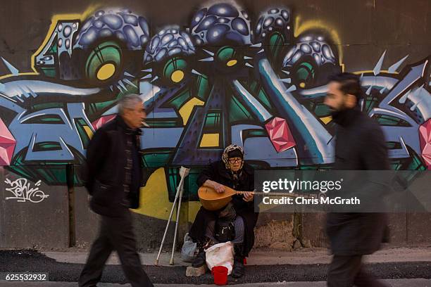 People walk past a woman busking on Istanbul's famous Istiklal shopping street on November 24, 2016 in Istanbul, Turkey. European Parliament today...