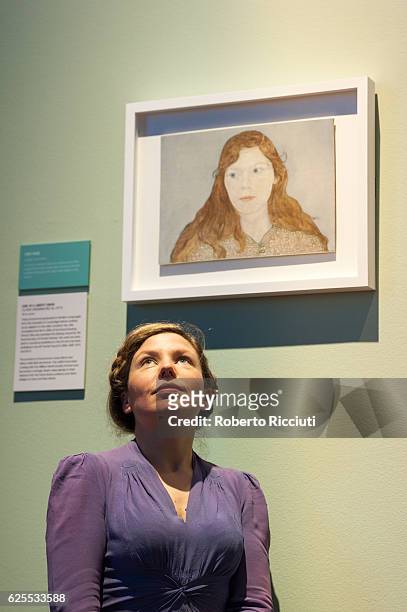 English artist Clara Drummond poses under her portrait 'Girl in a Liberty Dress' during the press launch of the exhibition 'BP Portrait Awards 2016'...