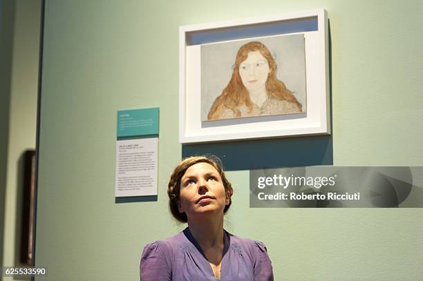 English artist Clara Drummond poses under her portrait 'Girl in a Liberty Dress' during the press launch of the exhibition 'BP Portrait Awards 2016'...