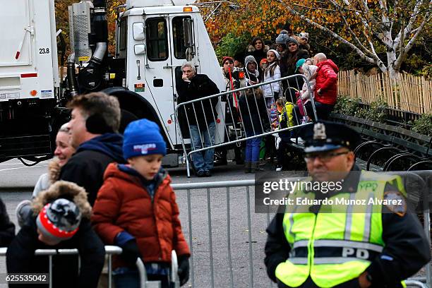 Officers stand guard next to trucks used to block the access to the parade as people arrive to watch the 90th Macy's Annual Thanksgiving Day Parade...