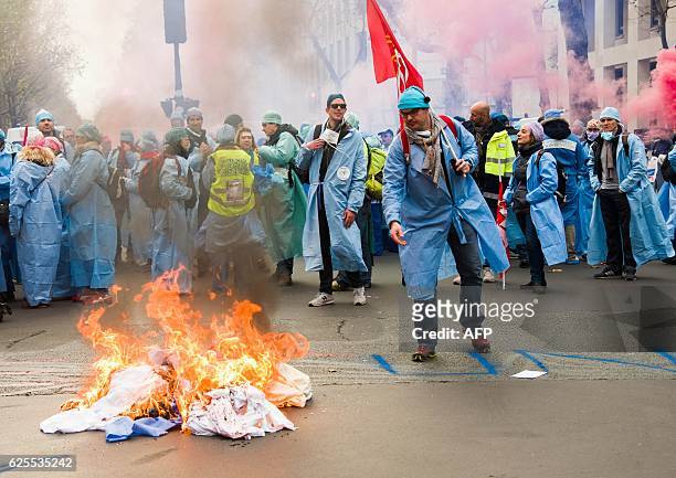 Anesthetists and student anesthetists display placards stand by a fire lit in the road during a demonstration in Paris on November 24, 2016 calling...