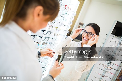 Femme essayant des lunettes dans un magasin d’optique Femme essayant des lunettes dans un magasin d’optique